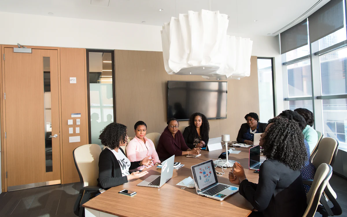 A person presenting to colleagues around a table of laptops
