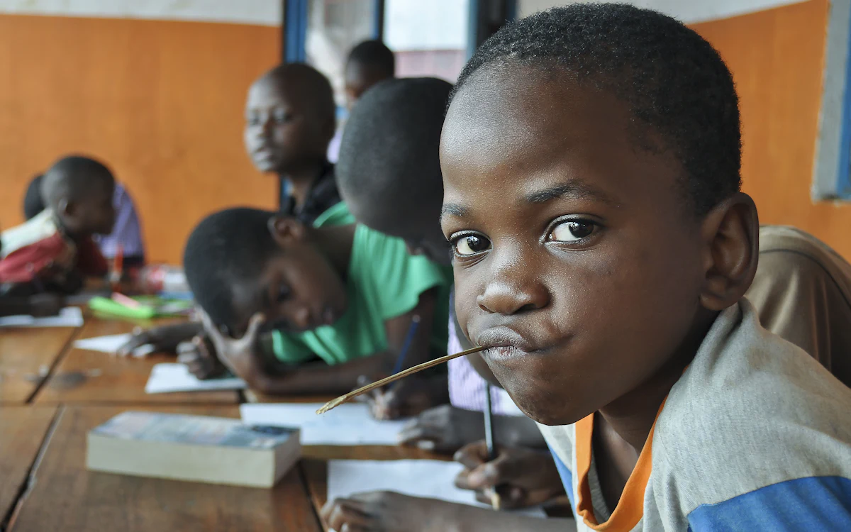 Children writing at a shared desk with exercise books and pencils